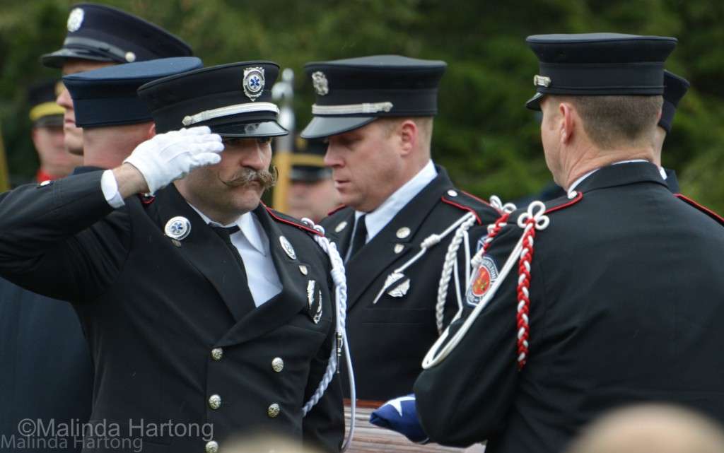 Having folded the flag covering Patrick Wolterman's casket, it's passed to Lt Nathaniel Robertson to give to Chief Dawson to present to Mrs Bre Wolterman, just wed to Patrick in May of this year and now a widow. ©Malinda Hartong
